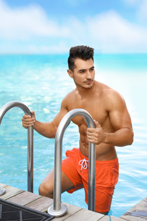 Young man getting out of outdoor poolの写真素材