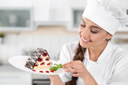 Professional female chef with plate of delicious dessert in kitchenの写真素材