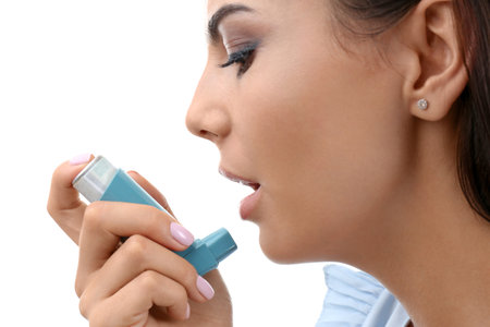Young woman using asthma inhaler on white background, closeupの写真素材