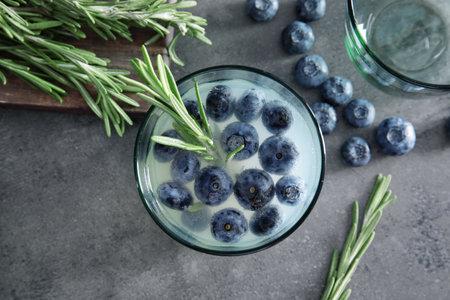 Flat lay composition with glass of blueberry and rosemary cocktail on gray tableの写真素材
