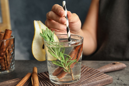Woman holding glass cocktail with rosemary on table, closeupの写真素材