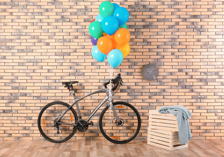 Bicycle with colorful balloons near brick wall indoorsの写真素材