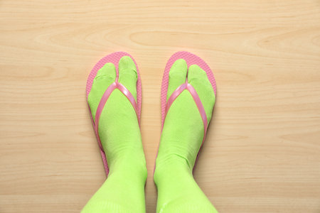 Woman wearing bright socks with flip-flops standing on floor, top viewの写真素材