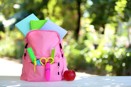 Backpack with school stationery on table outdoorsの写真素材