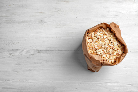 Bag of rolled oat on light background, top view with space for text. Whole grain cereal