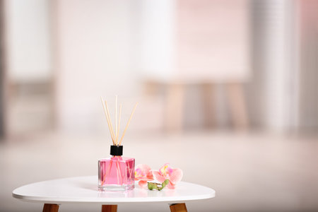 Aromatic reed air fresher and flowers on table against blurred backgroundの写真素材