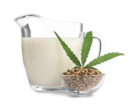 Bowl with hemp seeds and jug of milk on white backgroundの写真素材