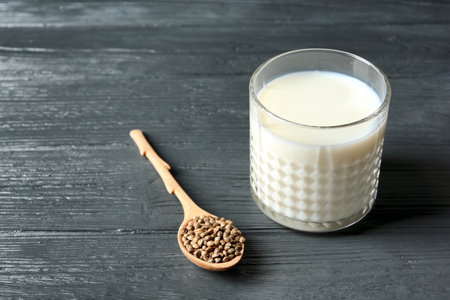 Glass of hemp milk and spoon with seeds on wooden backgroundの写真素材