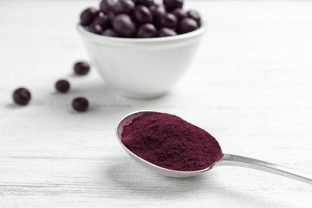 Spoon with acai powder and fresh berries on light wooden tableの写真素材