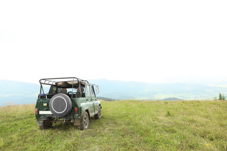 Dirty car on green hill in wilderness