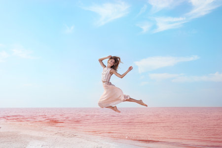Beautiful woman posing near pink lake on sunny dayの写真素材