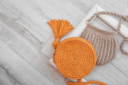 Knitted bags and space for design on wooden background, flat layの写真素材