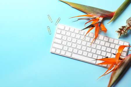 Creative flat lay composition with tropical flowers and computer keyboard on color backgroundの写真素材