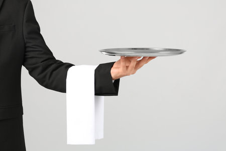 Waiter holding metal tray on light backgroundの写真素材