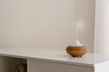 Aroma oil diffuser lamp on cabinet against light backgroundの写真素材