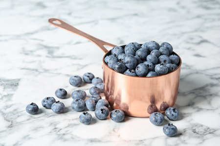 Cookware with juicy and fresh blueberries on marble tableの写真素材
