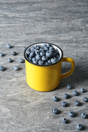 Fresh blueberries in yellow cup on color tableの写真素材