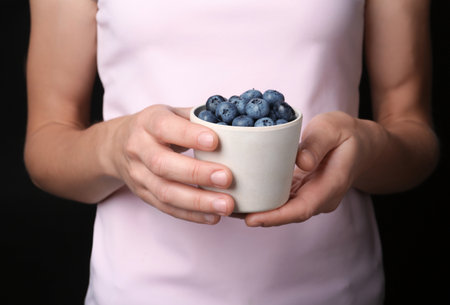 Woman holding crockery with juicy fresh blueberries in hands, closeup viewの写真素材