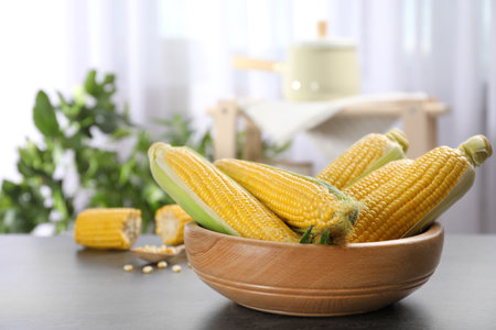 Bowl with tasty sweet corn cobs on table