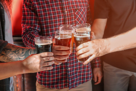 Group of friends clinking glasses with beer on color backgroundの写真素材