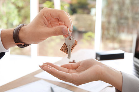 Real estate agent giving key to woman in office, closeupの写真素材