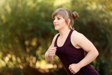 Young woman running in park on sunny dayの写真素材