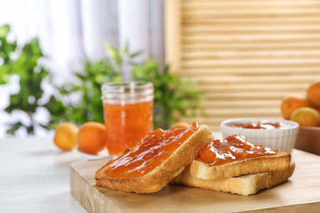 Bread with tasty apricot jam on wooden boardの写真素材