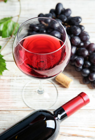Glass and bottle of red wine with fresh ripe juicy grapes on tableの写真素材