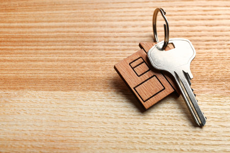 Key with trinket in shape of house on wooden background. real estate agent servicesの写真素材