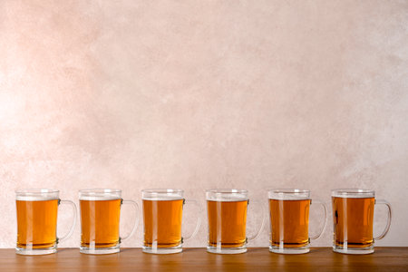Glass mugs with beer on table against color backgroundの写真素材