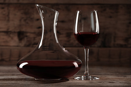 Elegant decanter and glass with red wine on wooden tableの写真素材