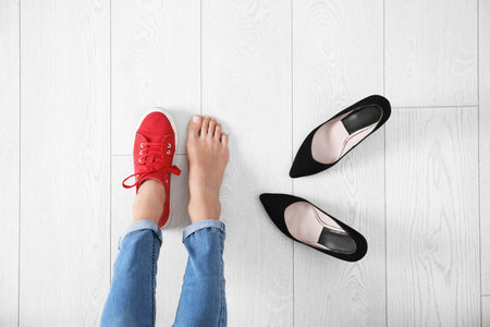 Young woman changing shoes on wooden background, top viewの写真素材