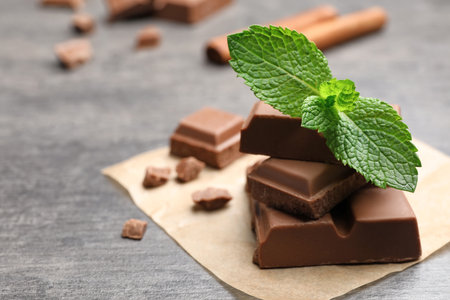Pieces of milk chocolate with mint on gray tableの写真素材