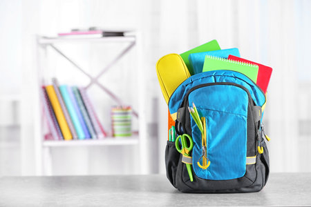 Backpack with school stationery on table indoorsの写真素材