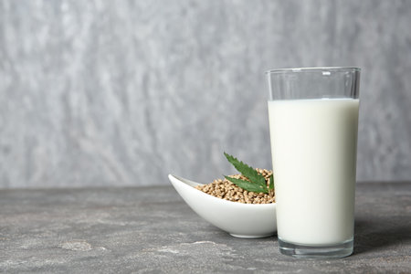 Glass of hemp milk, bowl with seeds and space for text on gray backgroundの写真素材
