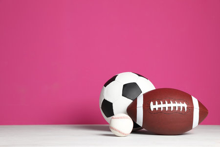 Different sport balls on table against color background. Space for textの写真素材