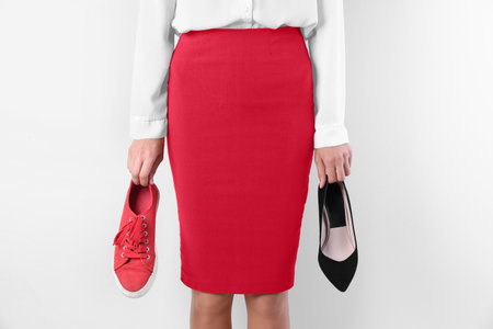 Woman holding high heeled shoe and sneaker on white background, closeup. Choice conceptの写真素材