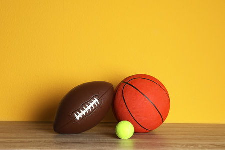 Different sport balls on table against color background. Space for textの写真素材