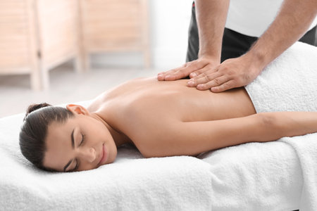 Relaxed woman receiving back massage in wellness centerの写真素材