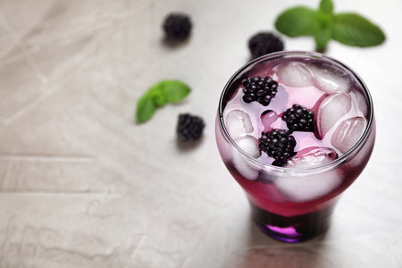 Glass with iced blackberry lemonade on gray tableの写真素材