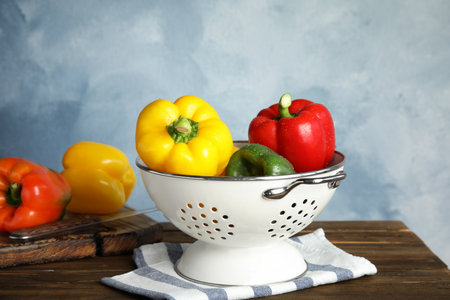 Colander with ripe paprika peppers on wooden tableの写真素材