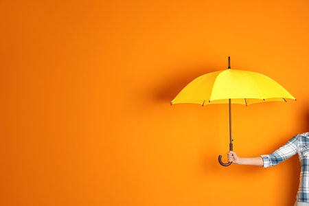 Woman holding beautiful umbrella on color background with space for designの写真素材
