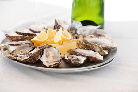 Fresh oysters with cut juicy lemon served on tableの写真素材
