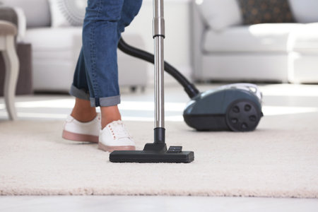 Woman cleaning carpet with vacuum cleaner, closeupの写真素材