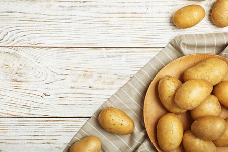 Fresh ripe organic potatoes on wooden background, top viewの写真素材