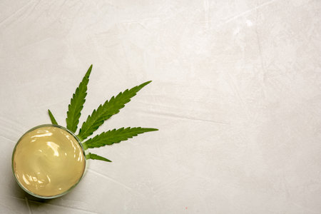 Glass with hemp lotion and space for text on gray background, top viewの写真素材