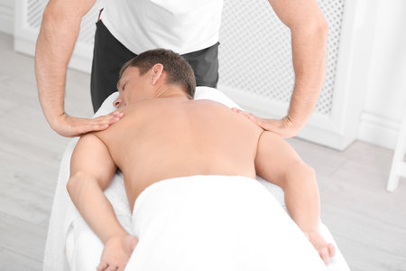 Relaxed man receiving back massage in wellness centerの写真素材