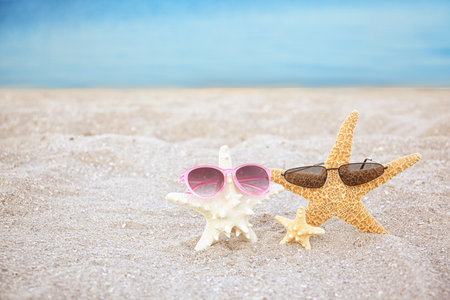 Starfish and sunglasses in sand on beach. Space for textの写真素材