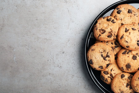 Plate with chocolate cookies and space for text on gray background, top view