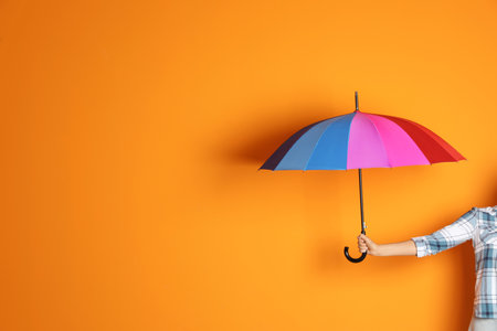 Woman holding beautiful umbrella on color background with space for designの写真素材